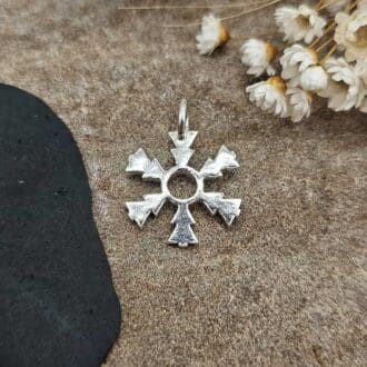 Handcrafted recycled polished sterling silver winter snowflake pendant not on chain but displayed on decorative stone