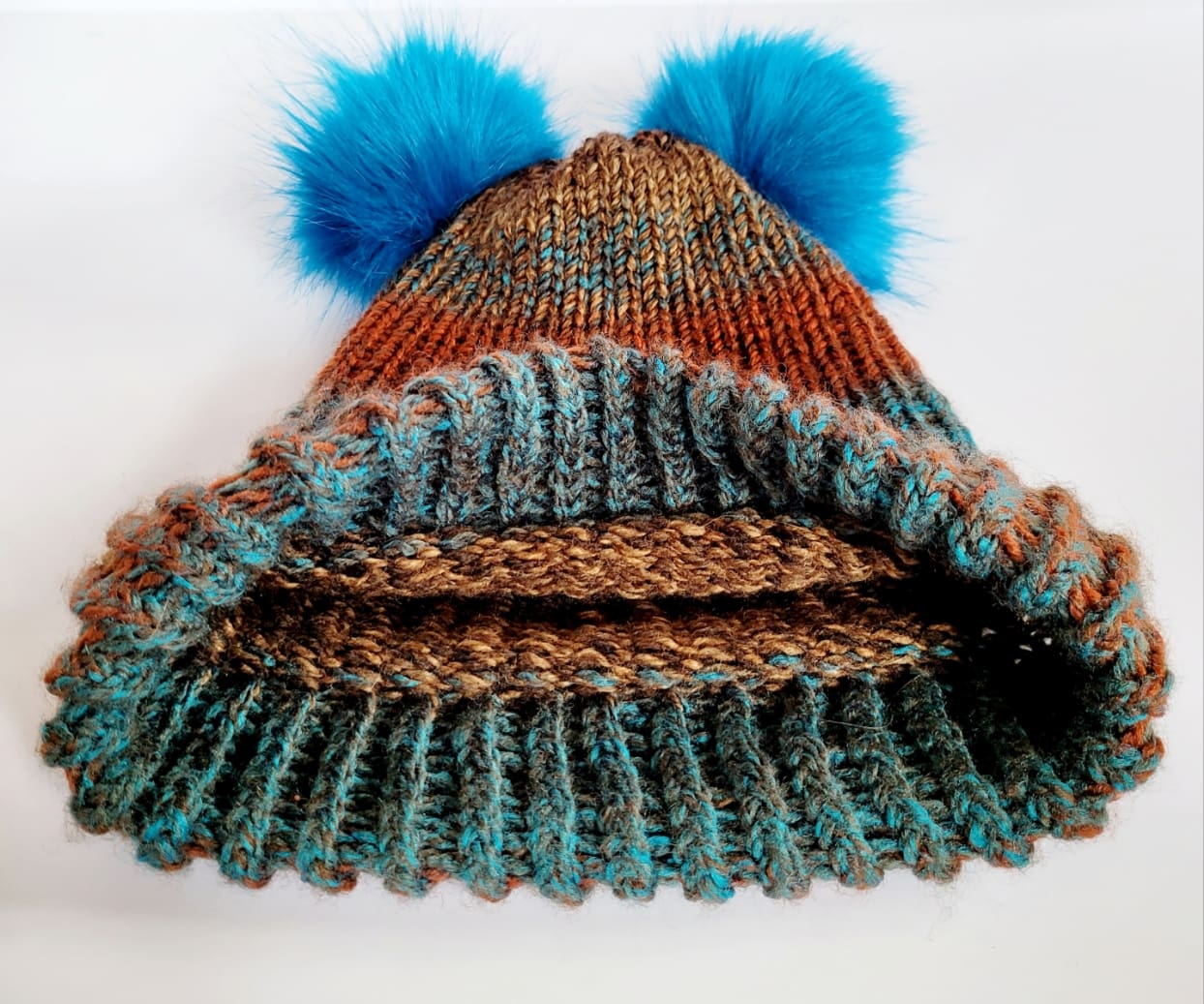 Brown and blue striped woolly hat with two fluffy blue pom poms on either side at the top