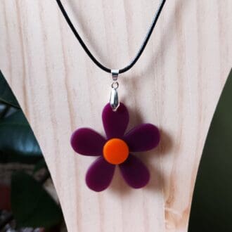 Purple and orange daisy pendant handmade in resin and fixed onto a black cord necklace.