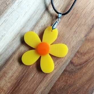 Retro Yellow daisy pendant with an orange centre, and hung from a black cord necklace.