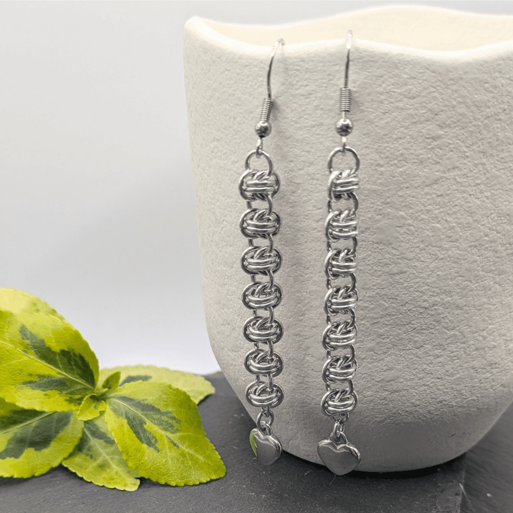 Chainmaille earrings made from aluminium. A length of barrel weave with a heart charm hanging from the bottom