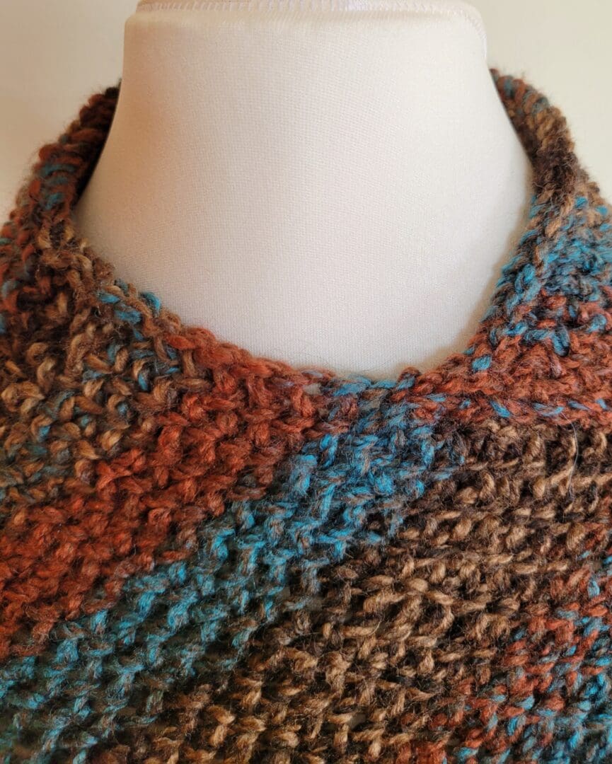 Brown and blue striped poncho with a round neck.