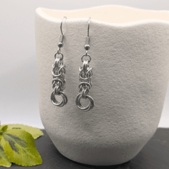 Chainmaille earrings made with silver aluminium rings. A short section of byzantine weave with a mobius (rose) at the bottom.