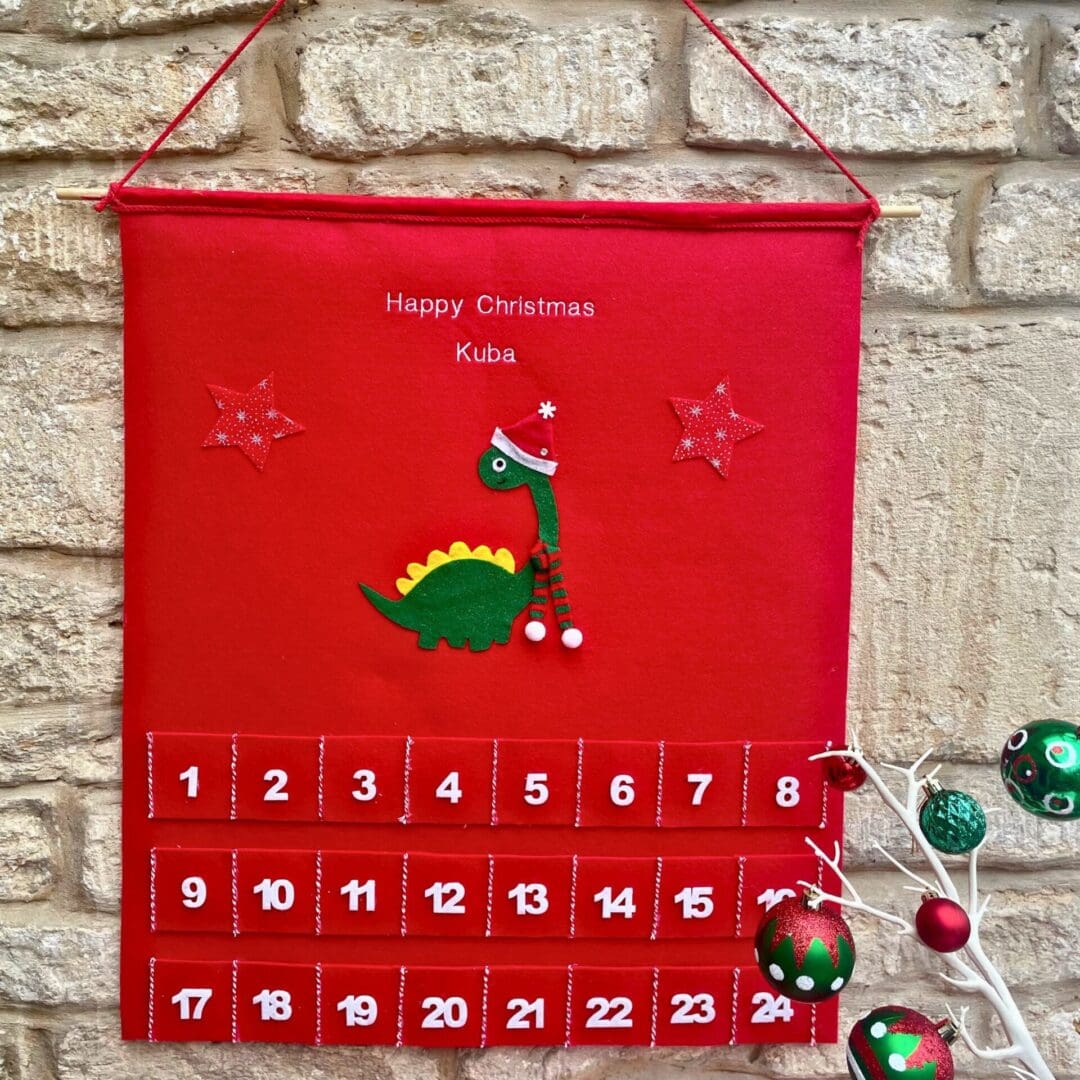 Personalised Christmas advent and matching stocking featuring a dinosaur dressed in a hat a scarf to keep himself warm