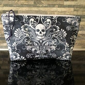 A medium-sized makeup bag in blue featuring Halloween skulls, complemented by a grey zipper and navy blue lining.