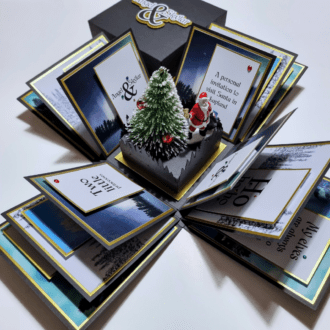 A black and gold exploding box for a surprise Lapland holiday opens with all panels on display. In the center, a Christmas tree and Santa figure are showcased. Surrounding panels contain details about the Christmas trip and the travel itinerary.