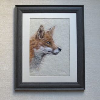 A handmade needle felted wool painting of a fox. The picture shows only the head of the fox and is looking to the right. It is framed in a dark grey frame with a cream mount.