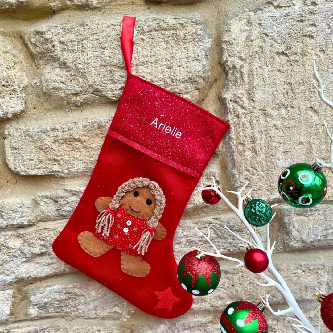 Christmas stocking featuring a gingerbread girl with a red sparkly dress and hair in pigtails