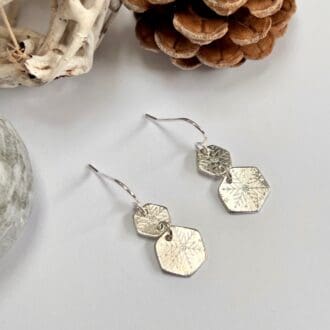 Handmade silver snowflake patterned earrings. Two hexagon charms attached to ear wire