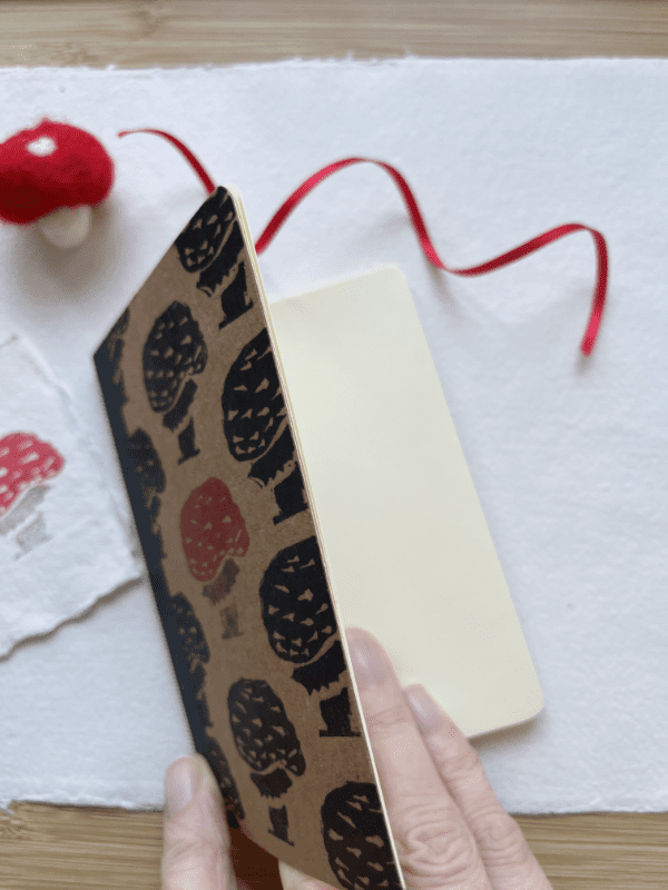 a mini notebook which has been block printed, slightly open to show blank off-white pages