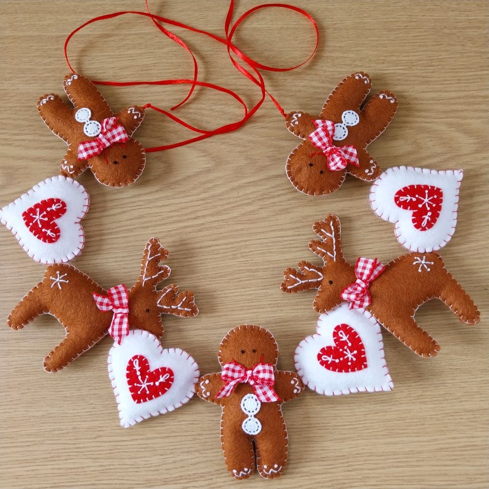 A handstitched and embroidered felt christmas garland, made up of gingerbread men, reindeer and hearts