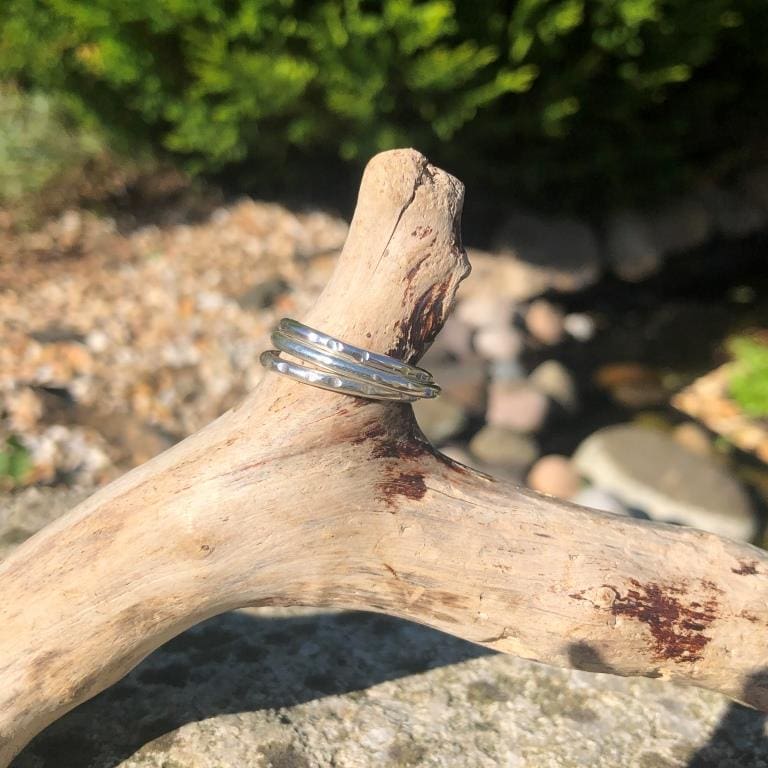 Three-Hammered-Recycled-Silver-Stacking-Notched-Rings-on-driftwood