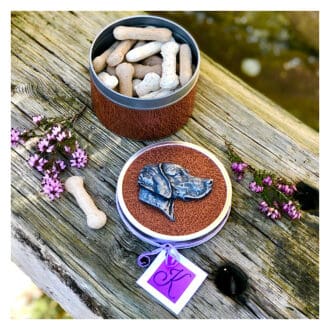 Circular Weimaraner dog treat tin with leatherette detail, and bone shaped treats inside. Dog portrait motif on the lid in cold-cast pewter.