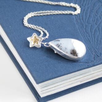 Dendrite opal gemstone set in silver with a silver and gold star.