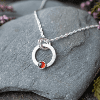 open circle silver necklace with small red garnet stone set at bottom