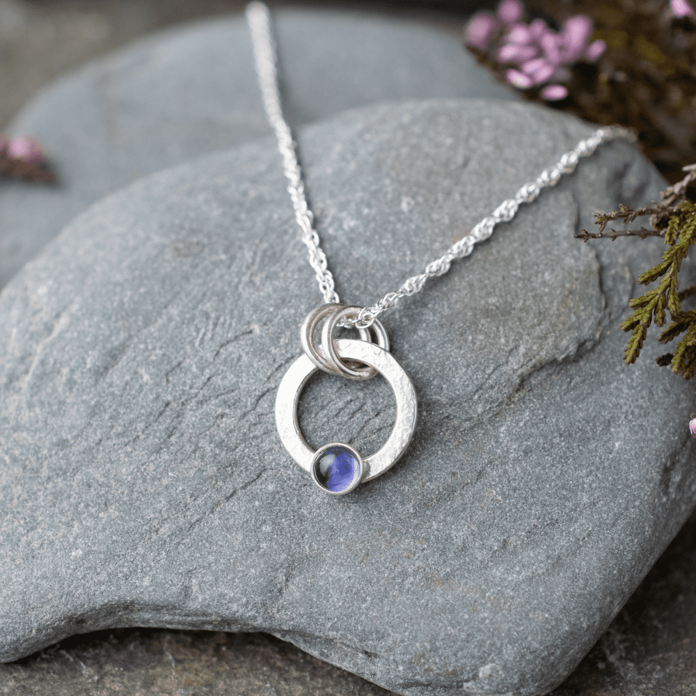 silver open circle necklace with small blue iolite gemstone set at bottom