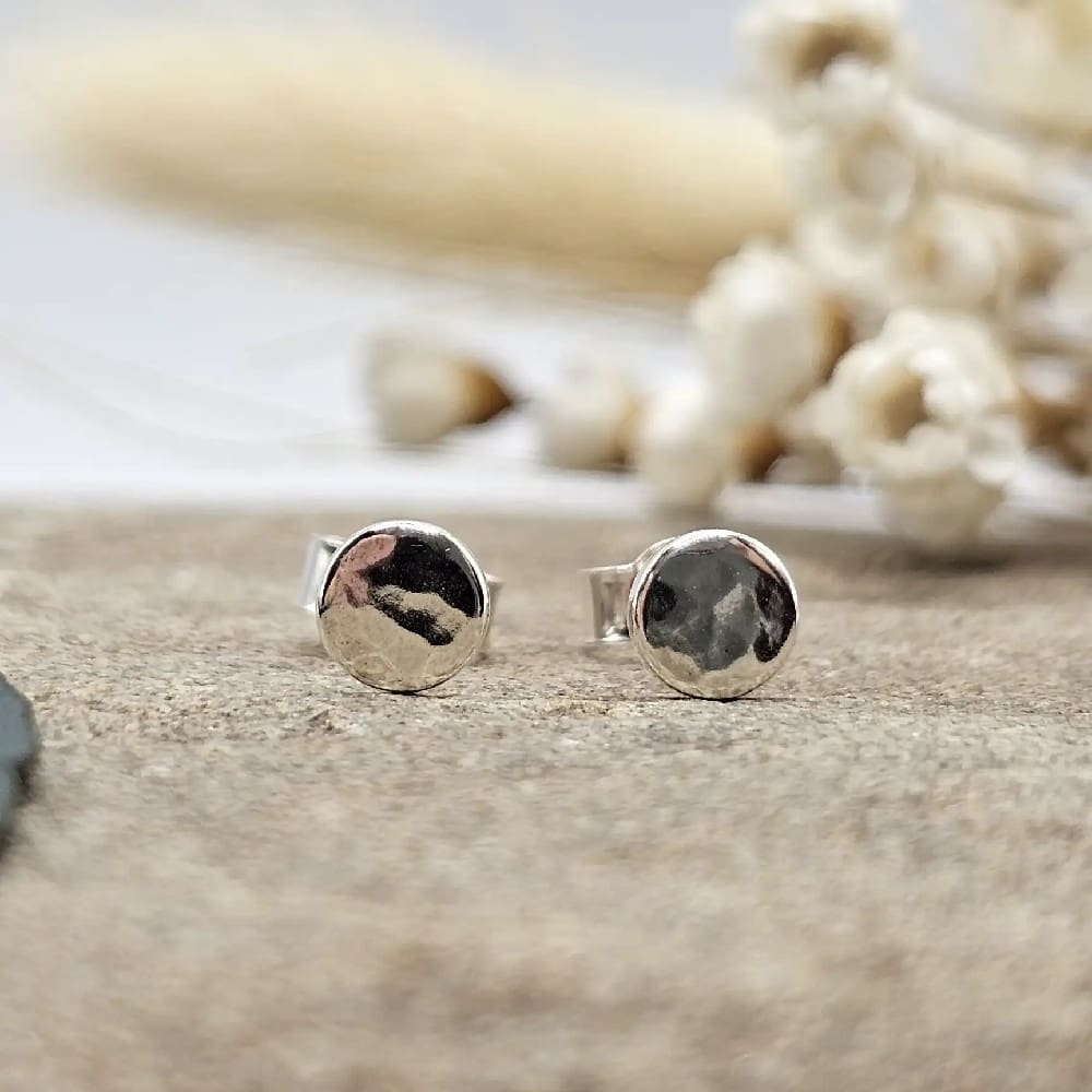 pair of handcrafted sterling silver rippled effect round 5mm stud earrings displayed on decorative stone