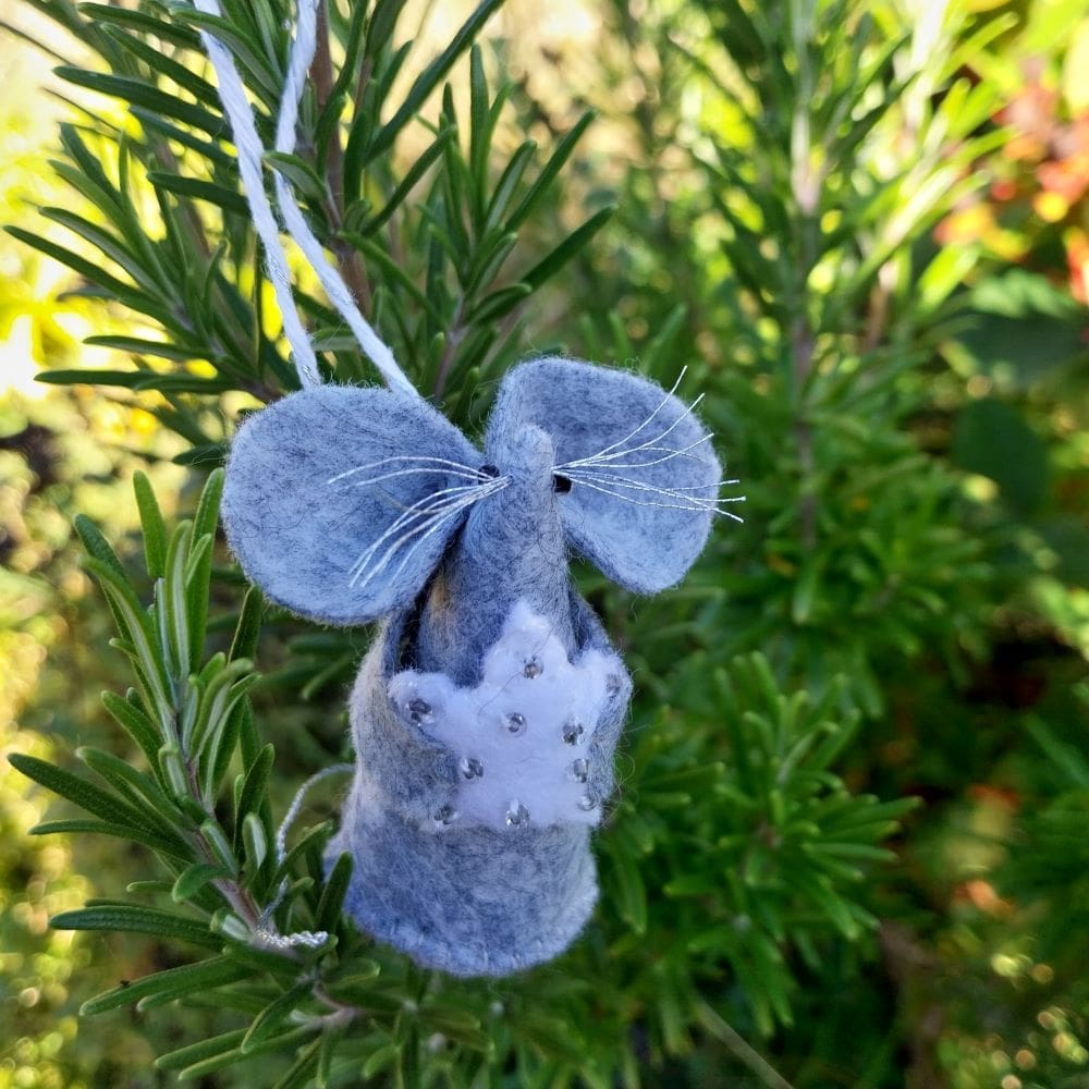 a hand stitched felt mouse holding a white star