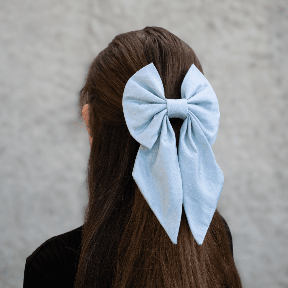 pale blue silk hair bow worn on back of head over half up half down hairstyle