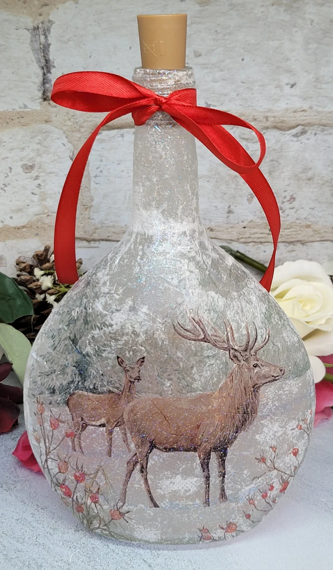 Round bottle with stag detailing. cork in the top and red ribbon tied around the neck in a bow