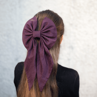 large silk hair bow in plum worn on back of head over half updo