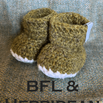 Pair of naturally dyed (using bog myrtle) green baby booties crocheted with a sheepskin sole in Hebridean wool by Midge Porter Design