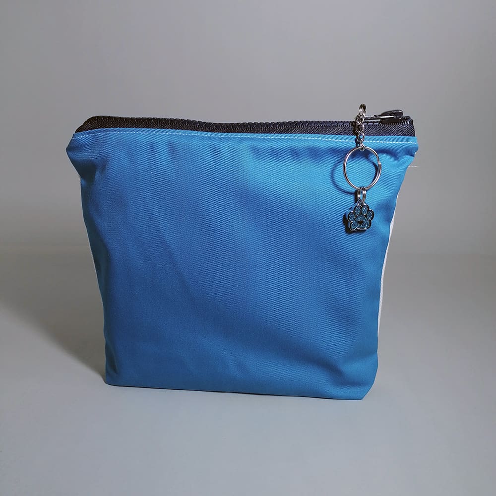 Charming washbag features an irresistible print of a polar bear sharing a bathtub with three penguins, perfect for any animal lover! Reverse in turquoise blue. Made from premium cotton with a water-resistant lining to protect against spills and an internal pocket. The chunky zipper fastening includes a chic chain and ring pull adorned with a bear paw charm, adding a fun touch of sparkle.