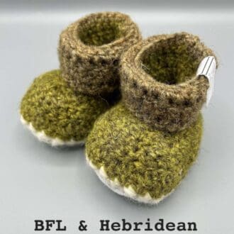 Pair of naturally dyed (using bog myrtle, nettle, moss and bark) two-tone green baby booties crocheted with a sheepskin sole in Hebridean and Blue Faced Leicester wool by Midge Porter Design