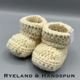 Pair of ecru baby booties crocheted with a sheepskin sole in handspun Scottish Blackface and Ryeland wool by Midge Porter Design