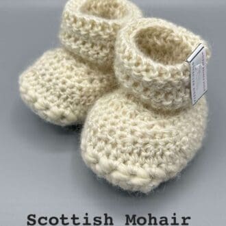 Pair of ecru baby booties crocheted with a sheepskin sole in Scottish Mohair and Shetland wool by Midge Porter Design