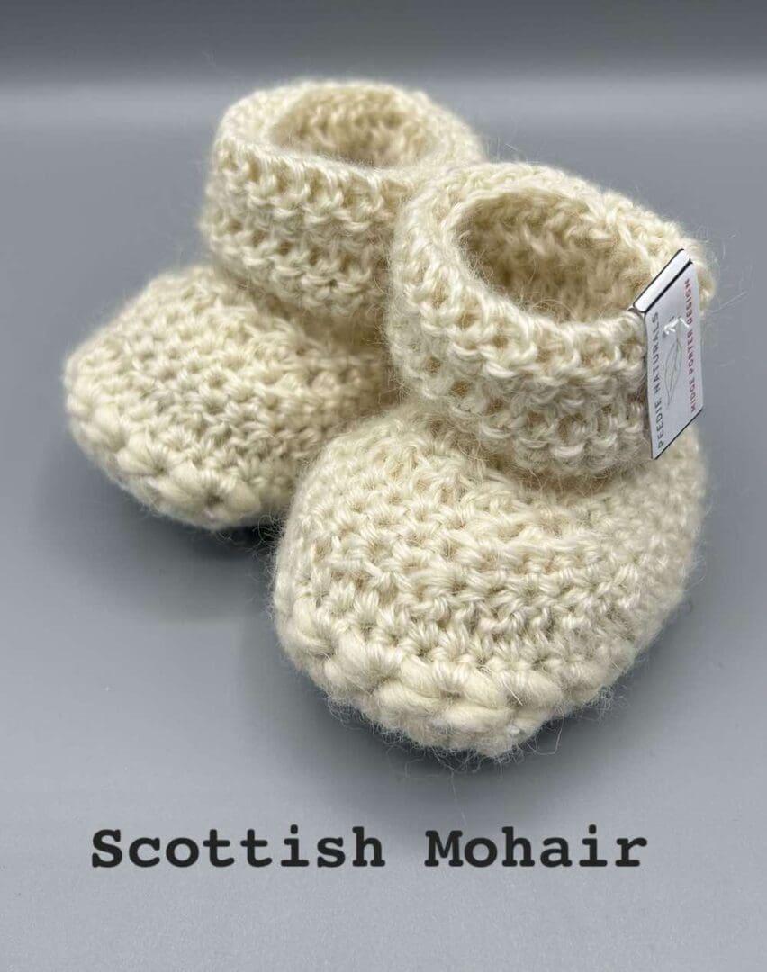 Pair of ecru baby booties crocheted with a sheepskin sole in Scottish Mohair and Shetland wool by Midge Porter Design