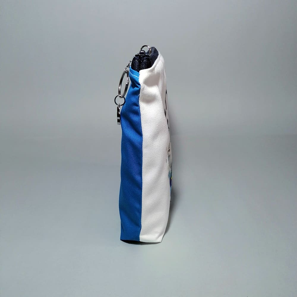 Side view of the Polar bear and penguins toiletries bag detailing the contrast of the printed face and blue reverse, chic chain and ring pull adorned with a bear paw charm, adding a fun touch of sparkle.