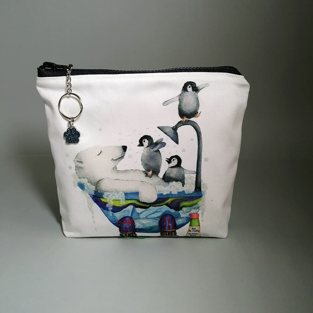 Charming washbag features an irresistible print of a polar bear sharing a bathtub with three penguins, perfect for any animal lover! Made from premium cotton with a water-resistant lining to protect against spills and an internal pocket. The chunky zipper fastening includes a chic chain and ring pull adorned with a bear paw charm, adding a fun touch of sparkle.