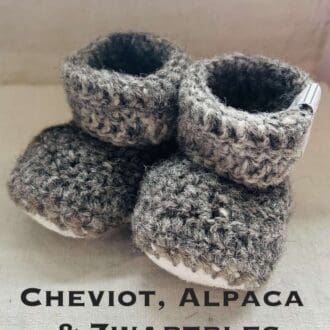 Pair of dark grey baby booties crocheted with a sheepskin sole in Cheviot, Zwartbles and Alpaca wool by Midge Porter Design