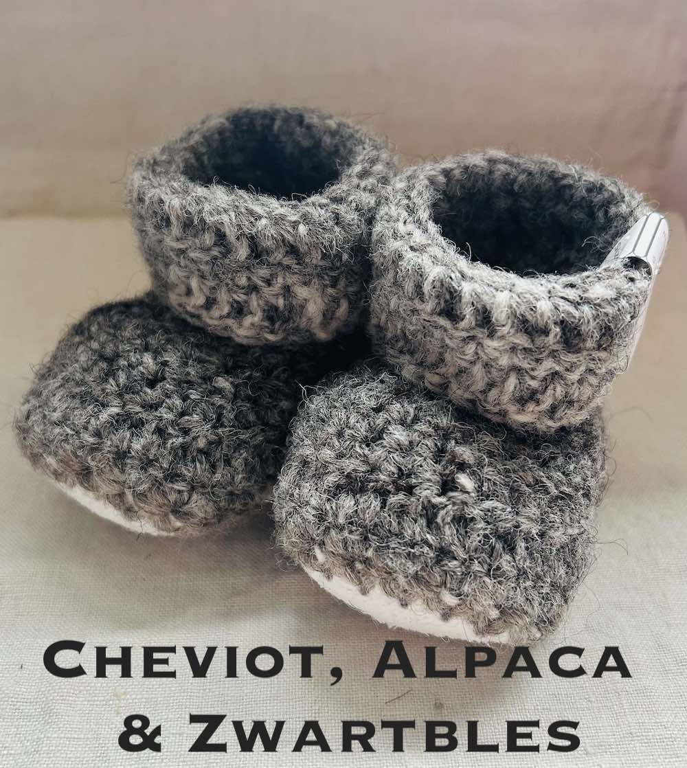 Pair of dark grey baby booties crocheted with a sheepskin sole in Cheviot, Zwartbles and Alpaca wool by Midge Porter Design