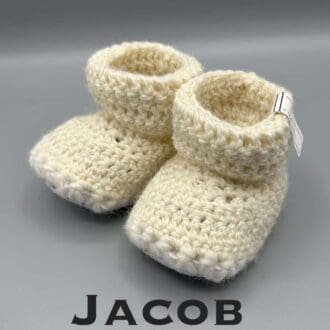 Pair of ecru baby booties crocheted with a sheepskin sole in Jacob wool by Midge Porter Design