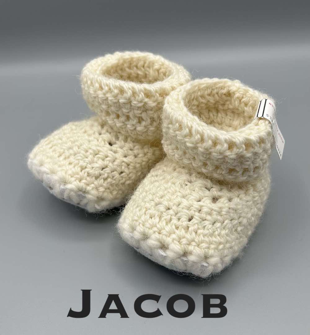 Pair of ecru baby booties crocheted with a sheepskin sole in Jacob wool by Midge Porter Design