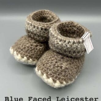 Pair of beige variegated baby booties crocheted with a sheepskin sole in Bluefaced Leicester and Bluefaced Kerry Hill wool by Midge Porter Design