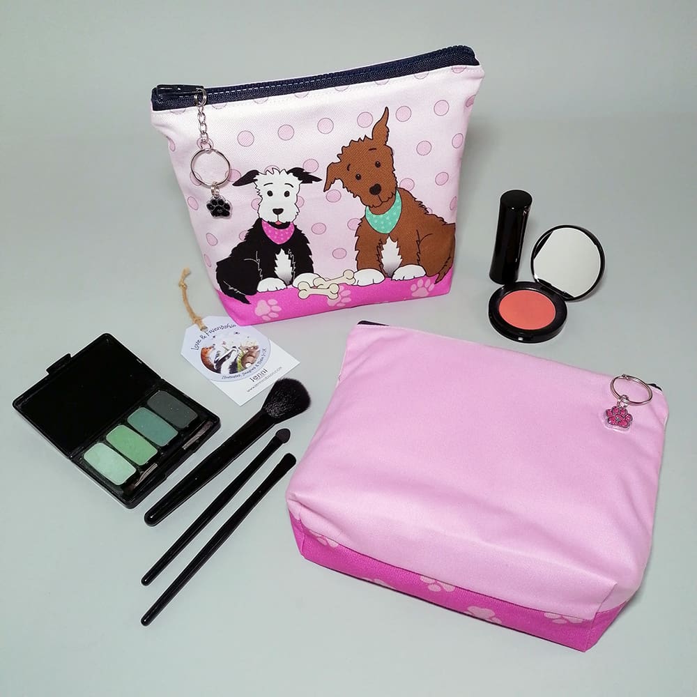 Two cute pups cosmetic bags with a pink reverse. Each has a chunky zip with a chain and ring zip pull and a sparkly paw charm