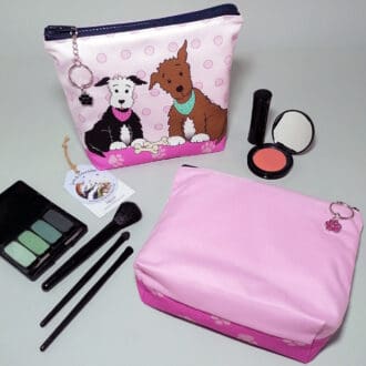 Two cute pups cosmetic bags with a pink reverse. Each has a chunky zip with a chain and ring zip pull and a sparkly paw charm