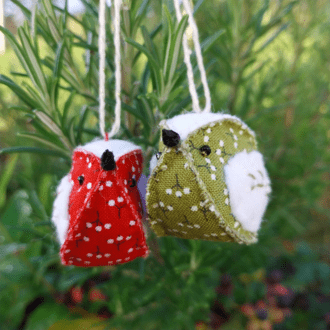 Apair of felt and fabric hand crafted birds with a berry patterened fabric. One red and one green