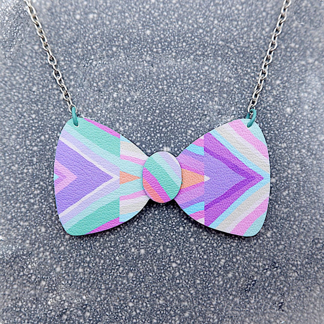 Pastel rainbow, handmade bow necklace. Fairy Kei inspired. Close up on grey speckled plate