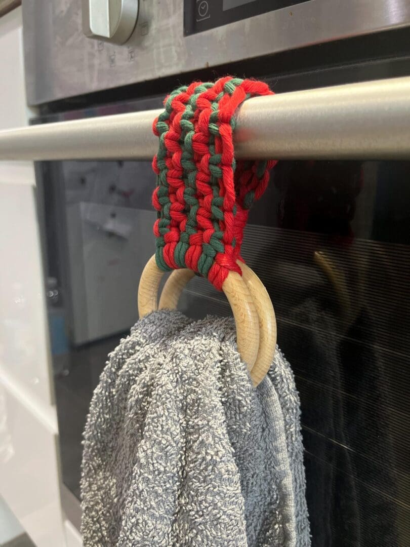 Handmade macrame tea towel holder, in festive Christmas colours of red and green, made with recycled cotton