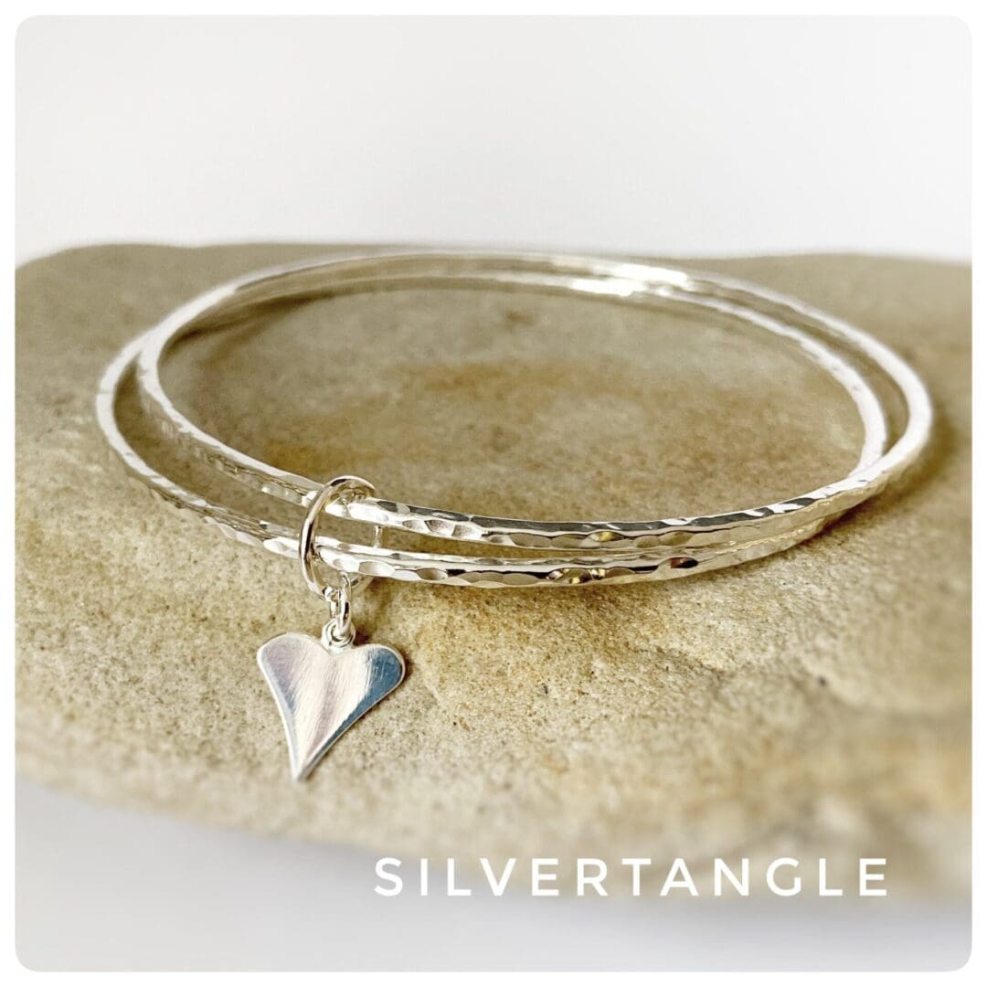 Two hammered silver bangles joined together with a silver heart charm