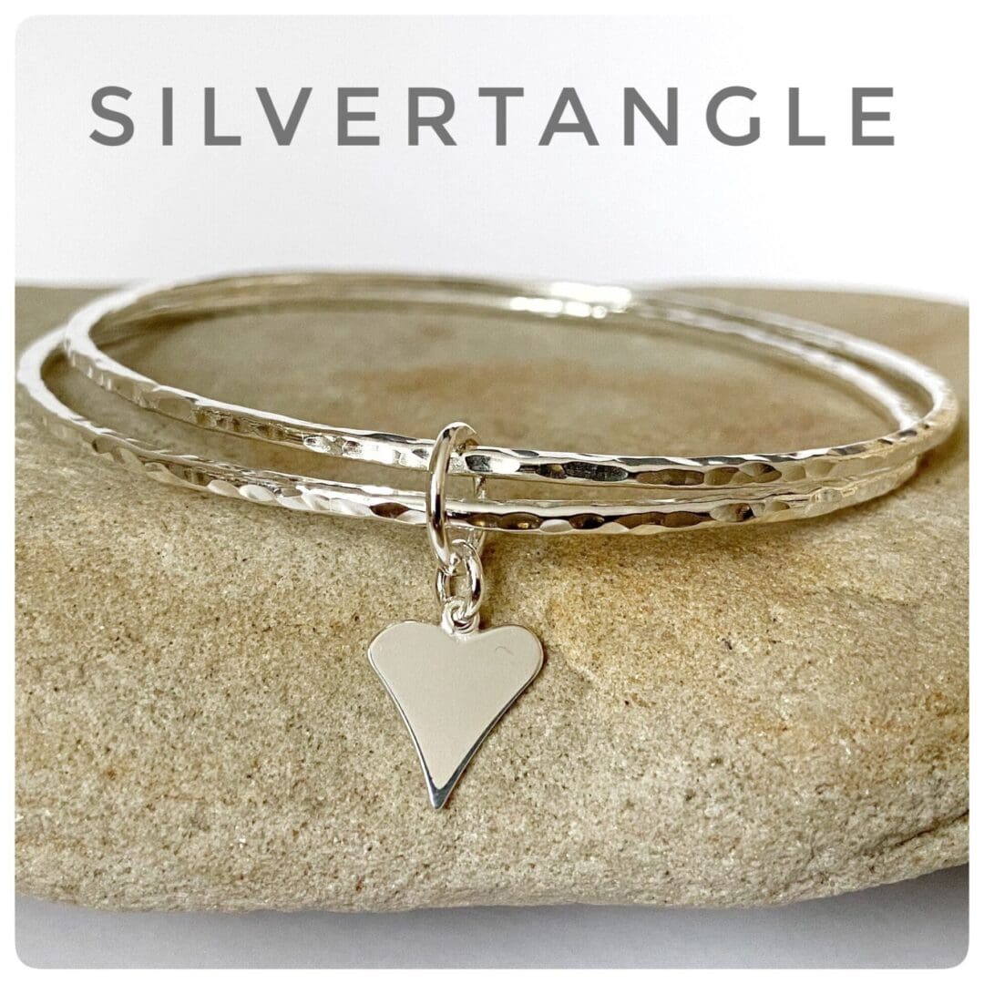 Two hammered silver bangles joined together with a silver heart charm