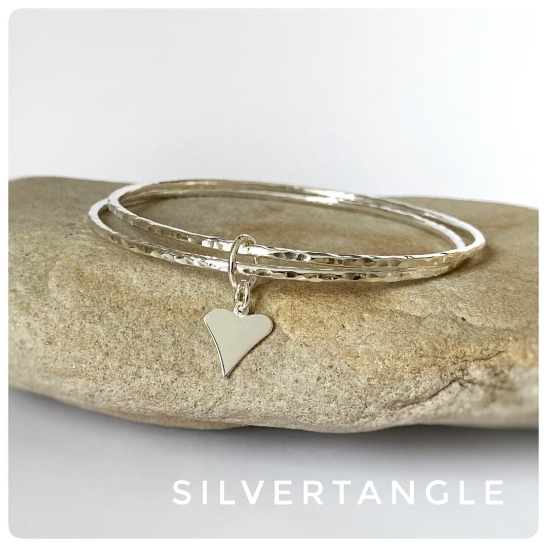 Two hammered silver bangles joined together with a silver heart charm