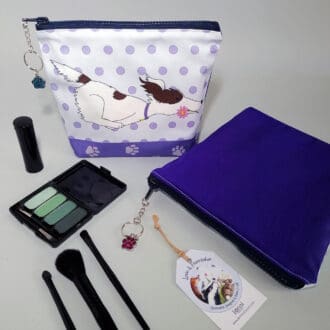 Dark purple and blue make up bag with a dog and daisy print, secured with a chunky zipper decorated with a paw print charm