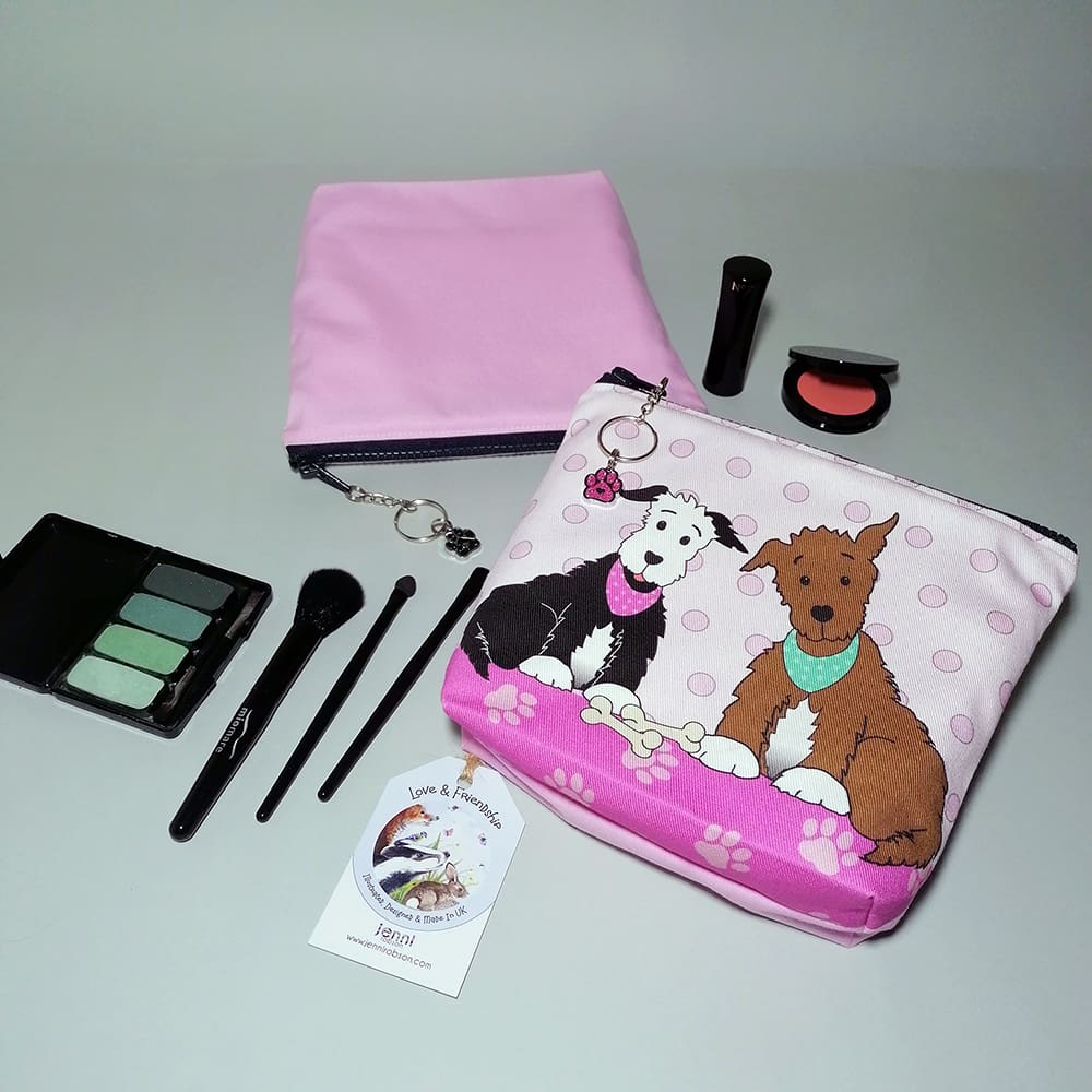 Two cute pups cosmetic bags with a pink reverse. Each has a chunky zip with a chain and ring zip pull and a sparkly paw charm