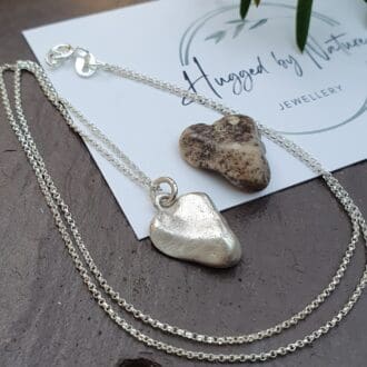 A silver heart pendant necklace in the shape of a stone, which is shown in the picture