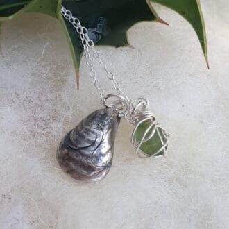 A silver mussell shell with aged patina and green sea glass charm necklace